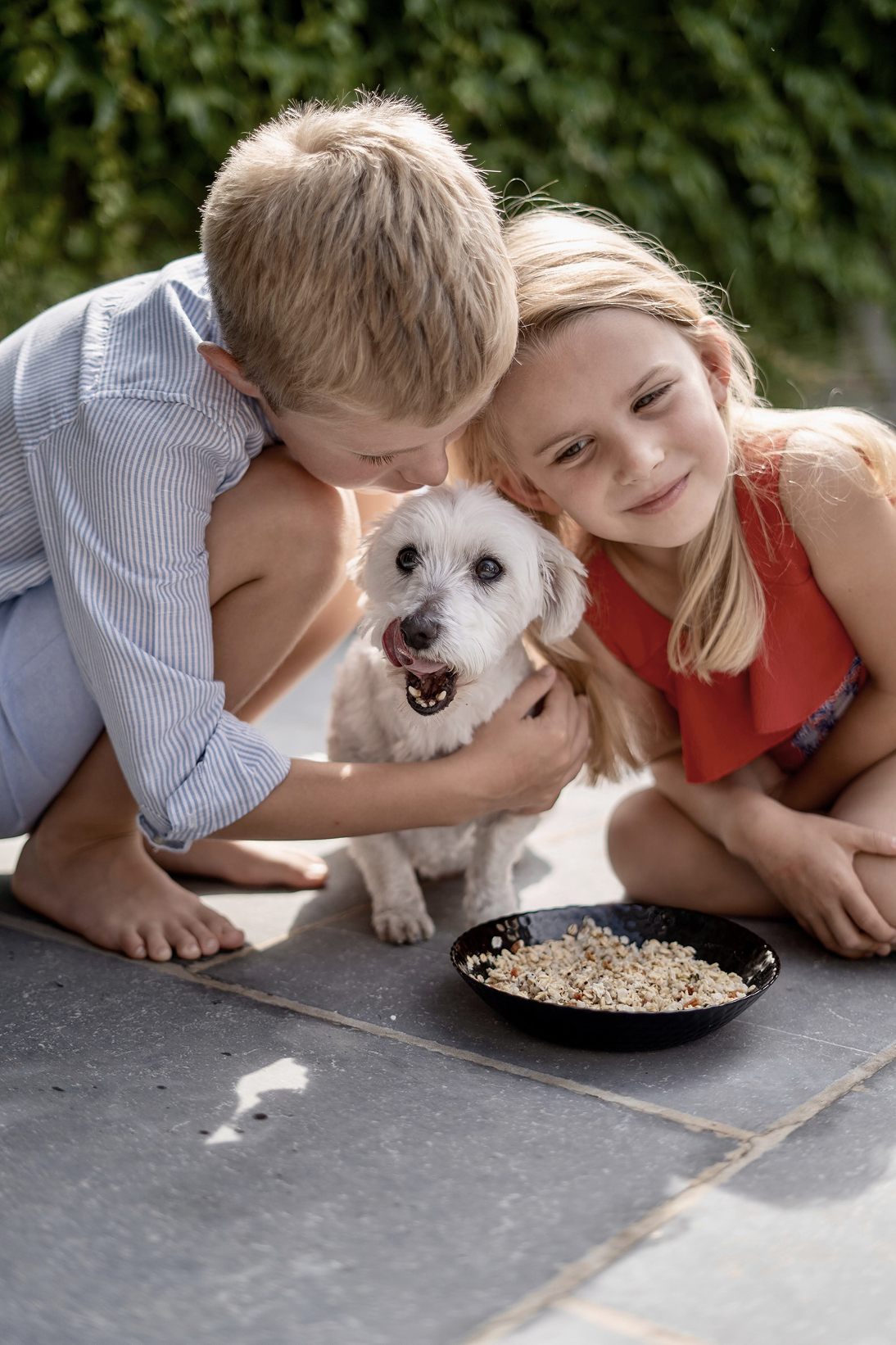 Deux enfants avec un chien devant une gamelle Sanalio